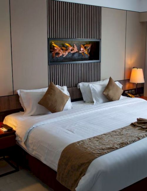 A cozy hotel room with a large bed, two bedside lamps, and modern decor. A small towel decoration sits on the bed.