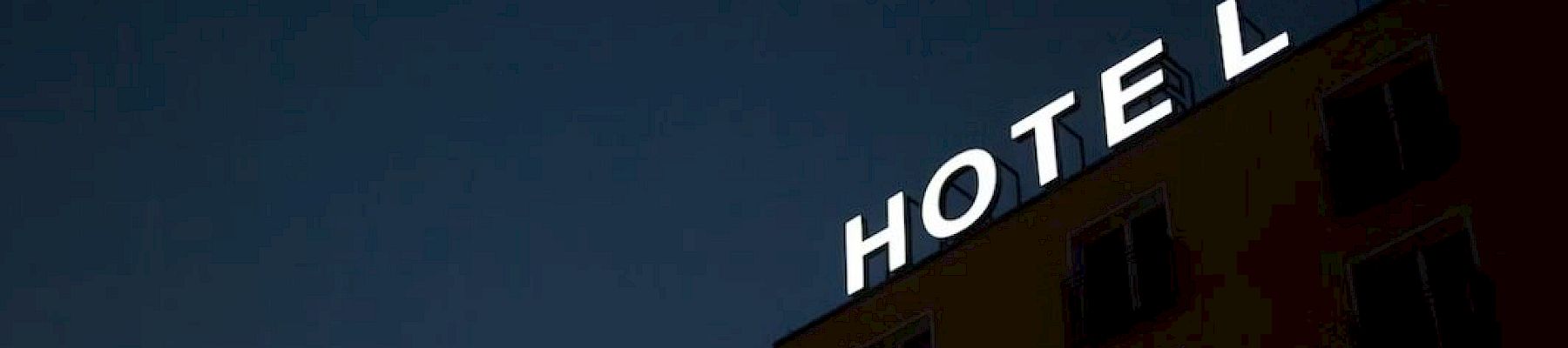 A building with the word "HOTEL" on top, missing the letter "H," against a dark sky.