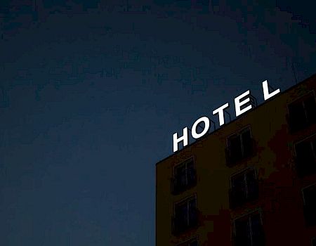 A building with the word "HOTEL" on top, missing the letter "H," against a dark sky.