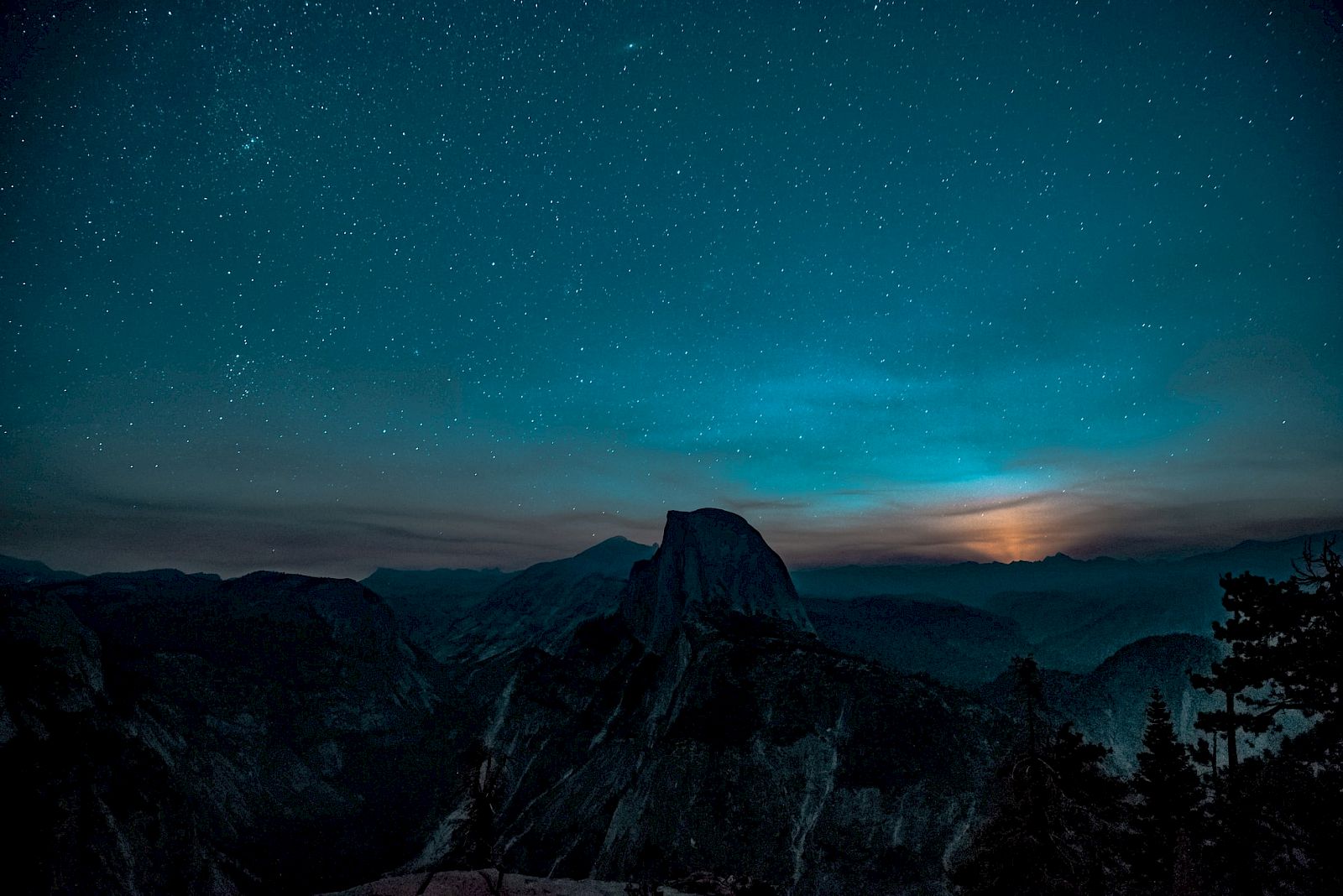 A stunning night sky filled with stars over silhouetted mountains and a glowing horizon.