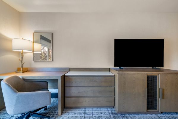A modern office setup with a desk, chair, lamp, TV, and cabinets, featuring a neutral color scheme and a simple, contemporary design.