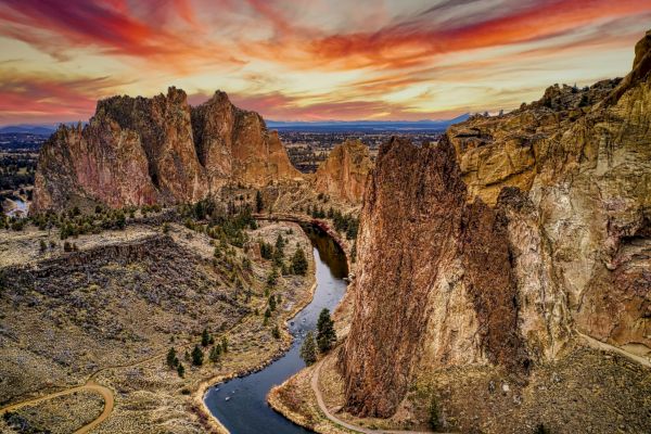 A stunning landscape with dramatic rock formations, a winding river, and a vibrant sunset sky.