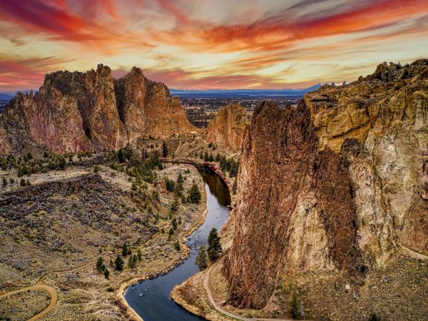 A stunning landscape with dramatic rock formations, a winding river, and a vibrant sunset sky.
