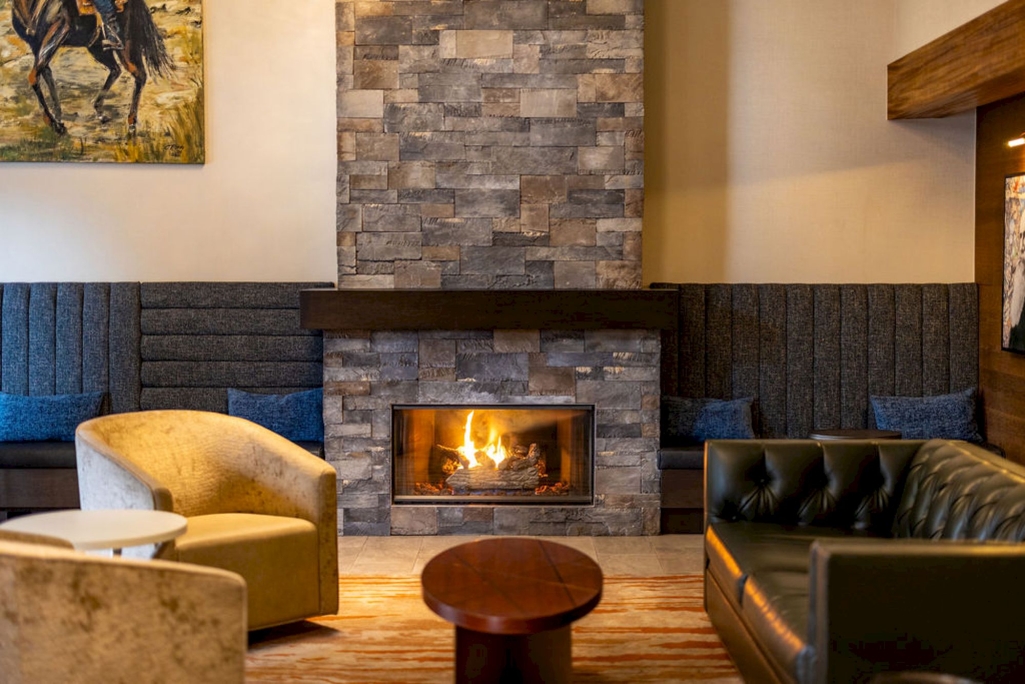 A cozy lounge with a stone fireplace, comfy seating, warm lighting, and a wood coffee table, perfect for relaxing by the fire.