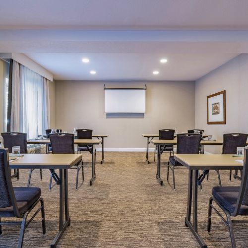 The image shows a small conference room with tables and chairs arranged in a classroom style setup, ready for a meeting or presentation.