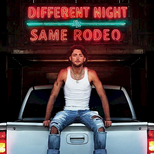 A man sits on the tailgate of a white pickup truck at night, under neon signs that read &ldquo;DIFFERENT NIGHT SAME RODEO.&rdquo;