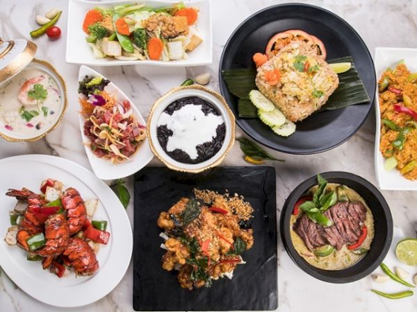 A colorful spread of flavorful dishes: seafood, curry, ribs, tofu, and vibrant sides presented on stylish plates. Top it off with a bright, inviting table vibe.