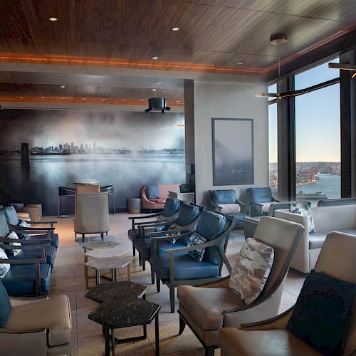 A modern, cozy lounge with plush seating, large windows showcasing a scenic view. Contemporary décor enhances the relaxing atmosphere.